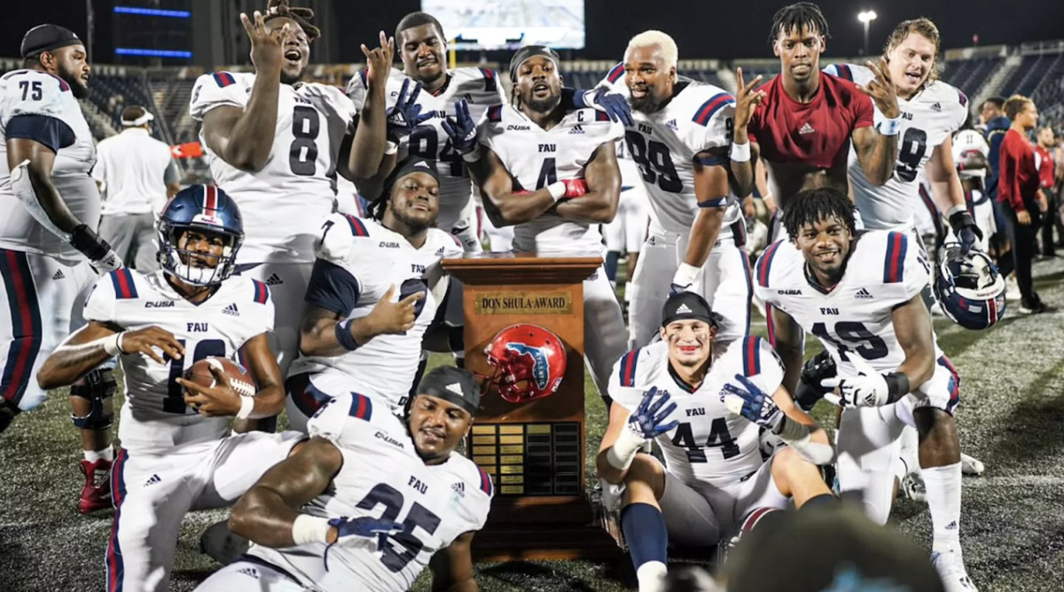 FAU players posing around the 2022 Don Shula Bowl trophy after defeating FIU 52-7. 